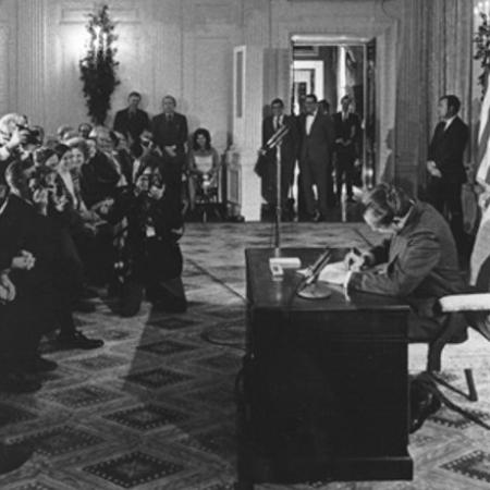 A historical picture of President Nixon seated at a desk, signing the National Cancer Act
